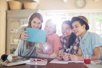 Group of smiling teenagers taking selfie in dining room