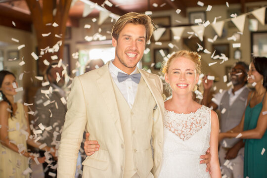 Portrait smiling young couple standing in falling confetti during wedding reception