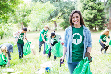 Portrait of smiling environmentalist volunteer picking up trash - Powered by Adobe