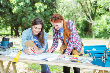 Smiling volunteers reviewing blueprints at construction site