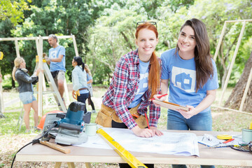 Portrait smiling volunteers digital tablet blueprints at construction site