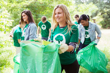 Smiling environmentalist volunteer picking up trash