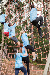 People climbing net on boot camp obstacle course