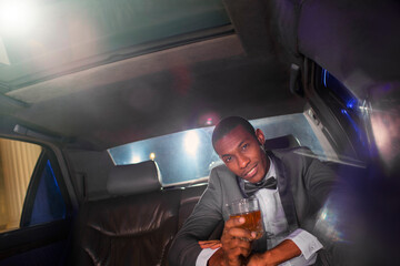 Portrait confident celebrity drinking cocktail inside limousine outside event