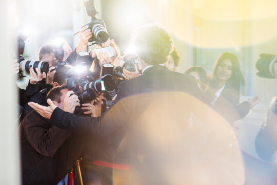 Celebrity being photographed by paparazzi at event