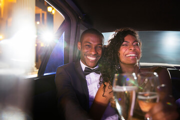 Laughing celebrity couple drinking champagne inside limousine at red carpet event