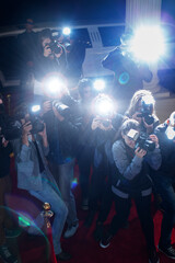 Paparazzi photographers pointing cameras at red carpet event