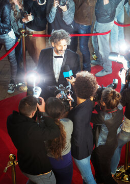 Celebrity being interviewed and photographed by paparazzi at event