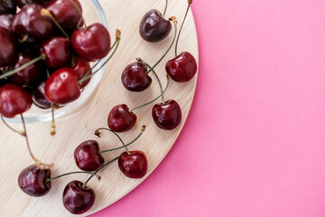 Sweet cherry on a wooden cutting board on a pink background.Summer sweet concept. Copy space for text