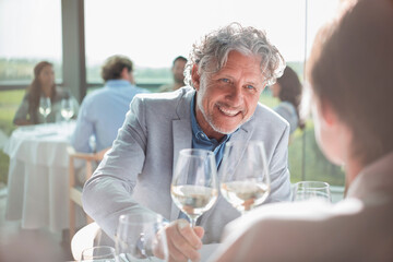 Smiling couple drinking wine in sunny restaurant