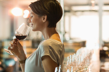 Woman wine tasting red wine in winery tasting room