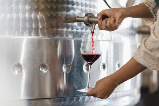 Vintner barrel tasting red wine from stainless steel vat