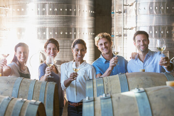 Portrait smiling winery employees barrel tasting in cellar