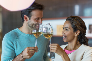 Smiling couple toasting white wine glasses