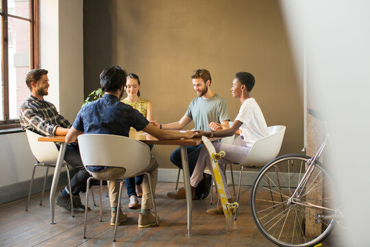 Creative business people holding hands at table in meeting