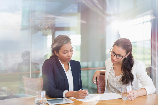 Businesswomen Reviewing Paperwork In Conference Room