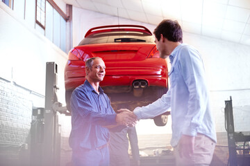 Mechanic and customer handshaking in auto repair shop