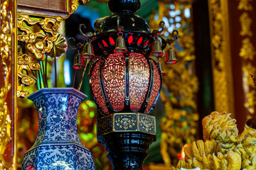Decorative Chinese lamp, porcelain vase and offerings in a Buddhist temple near the city of Danang, Vietnam. Closeup