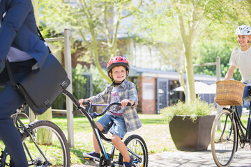 Portrait smiling boy in helmet riding tandem bicycle father in park