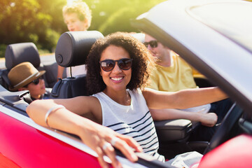 Portrait enthusiastic woman driving convertible with family - obrazy, fototapety, plakaty