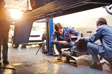Mechanics examining part in auto repair shop