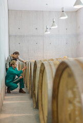 Vintners examining barrels in winery cellar