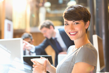 Portrait confident businesswoman drinking coffee in office