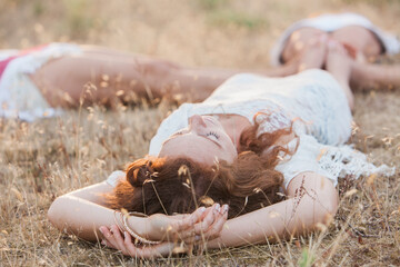 Boho women laying in circle with feet touching in rural field