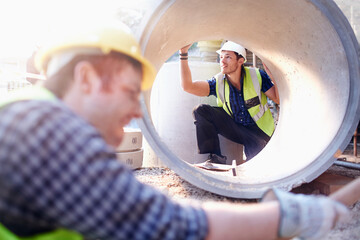 Construction worker examining concrete pipe