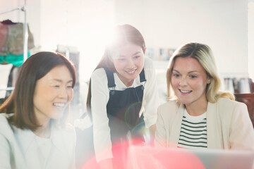 Smiling fashion designers working at laptop in office