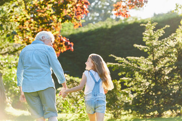 Grandmother granddaughter holding hands walking in sunny garden