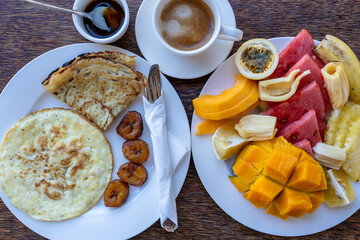 Tropical breakfast of fruit, coffee and fried eggs and banana pancake