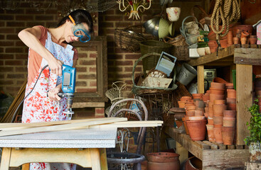 Woman using power sander in workshop - obrazy, fototapety, plakaty