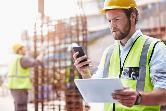 Construction worker digital tablet texting cell phone at construction site
