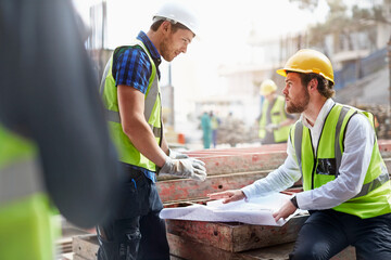 Construction worker engineer reviewing blueprints at construction site
