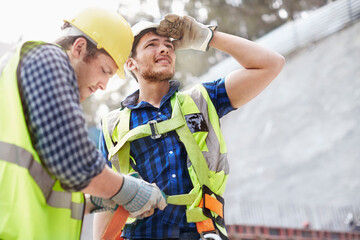 Construction worker fastening coworker‚Äôs safety harness - obrazy, fototapety, plakaty