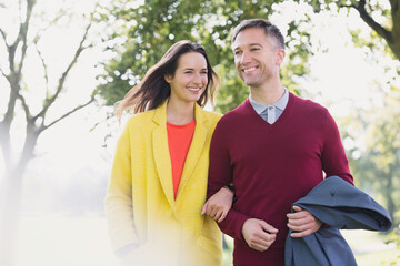 Obraz premium Couple walking arm in arm in park