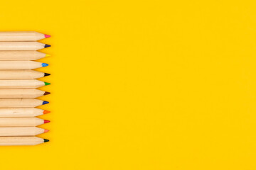 The concept of children's creativity and eco. Colored pencils made from wood on a yellow background close up with copy space