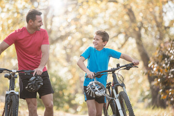 Obraz premium Father and son walking mountain bikes in woods