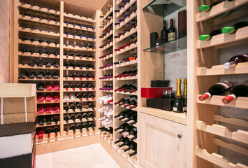 Wine bottles organized on racks in wine cellar - obrazy, fototapety, plakaty