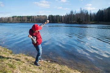 A child (boy) throws a stone at the lake