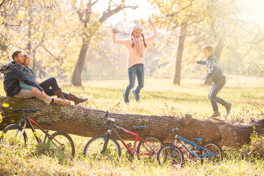 Family playing on fallen log in autumn woods