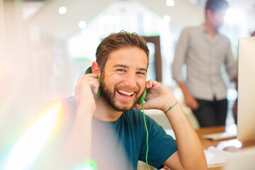 Portrait enthusiastic creative businessman listening to headphones in office