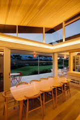 Illuminated slanted wood ceiling over long dining table