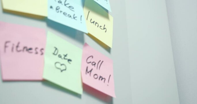 Close-up of multi-colored stickers with notes written with a marker and pasted on a gray board. Day plan. Copy space. Background.