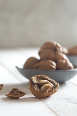 cracked walnut in front of a walnut bowl shot on white wood 