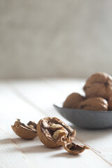 cracked walnut in front of a walnut bowl shot on white wood 