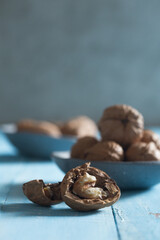 cracked walnut in front of a walnut bowl shot on blue wood 