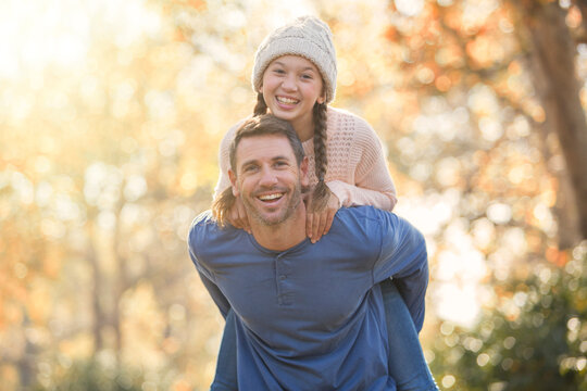 Portrait enthusiastic father piggybacking daughter outdoors