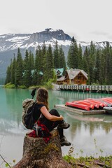 Hiking/adventurous girl overlooking beautiful wooden Emerald Lodge and red kayaks on Emerald Lake, Yoho National Park, British Columbia, Canada